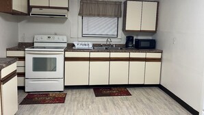 A compact kitchen with a stove, sink, microwave, and cabinets.