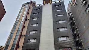 A multi-story building with a central entrance, large windows, and a parking area in front. - Hotel&Stay Heyyum - Juan (Incheon)