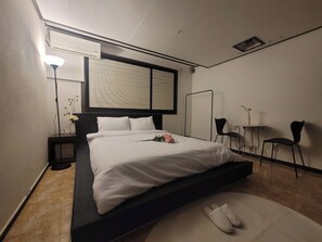 Una habitación de hotel moderna con una cama grande, mesitas de noche, un escritorio y una silla.