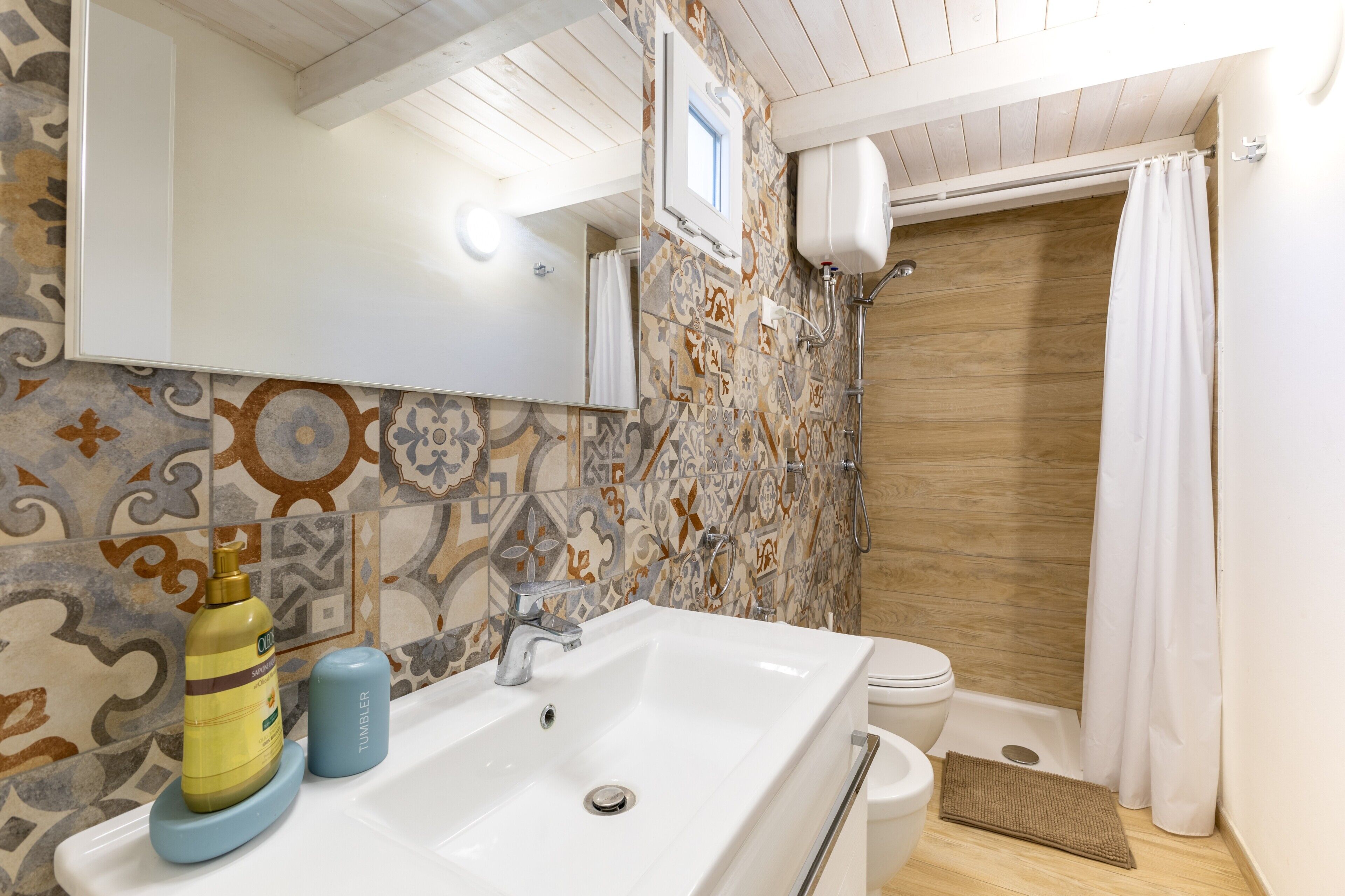 Un baño con un lavamanos blanco, un inodoro y una ducha con puerta de madera.