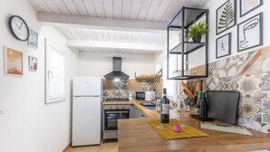 A modern kitchen with a wooden table, white appliances, and a black range hood. - Holiday Home 'Casa Felici In 2' with Private Pool, Wi-Fi and Air Conditioning (Santa Maria del Focallo)