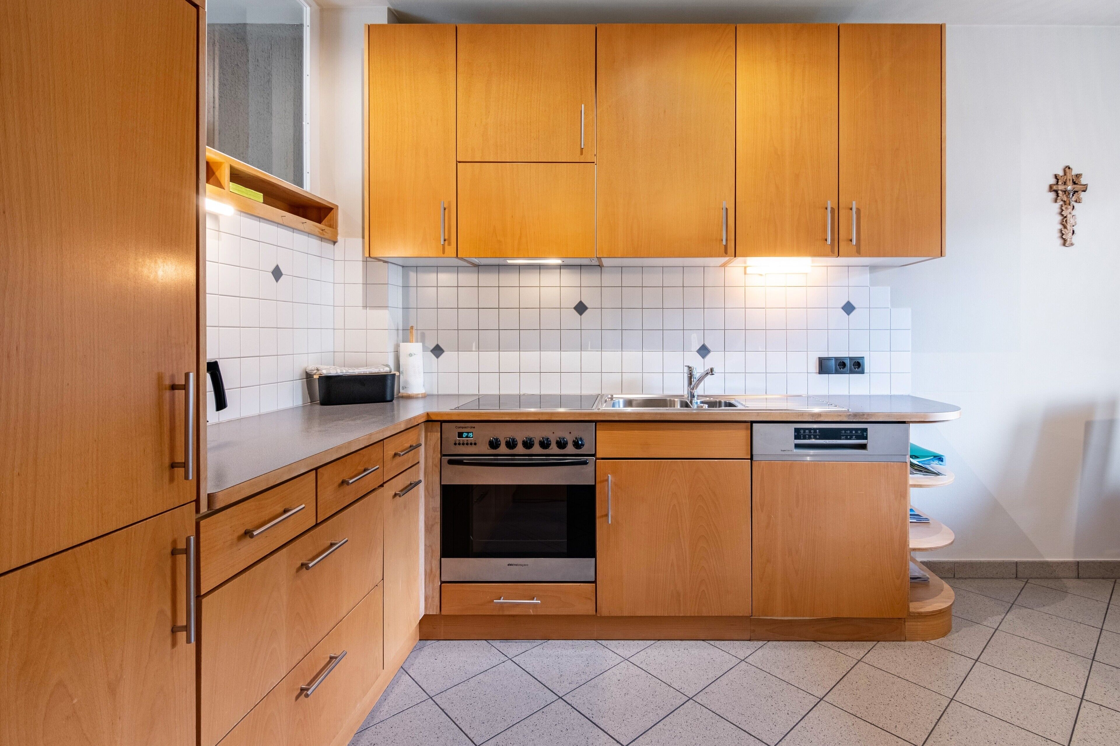 A modern kitchen with wooden cabinets, a built-in oven, and a dishwasher.
