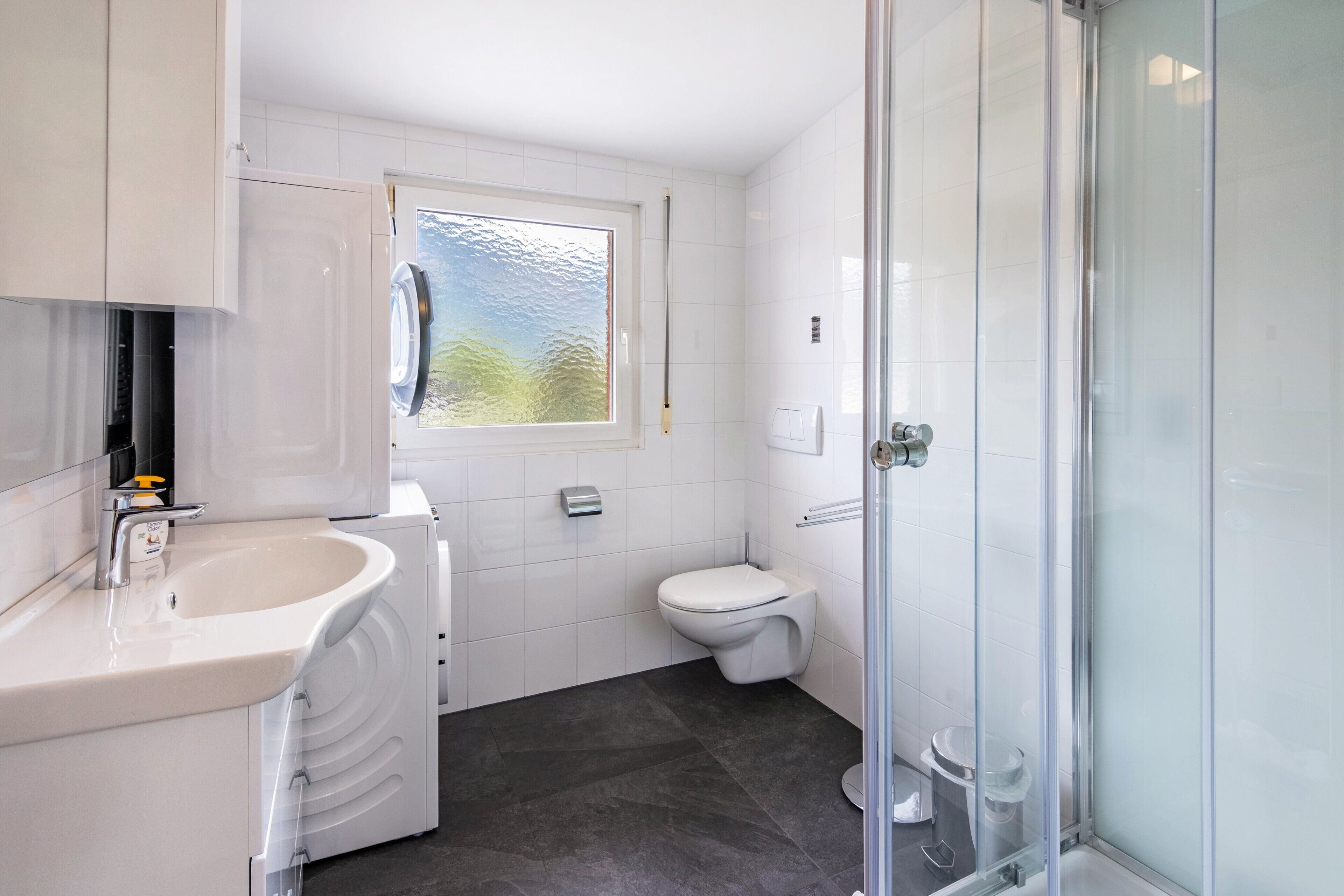 Ein modernes Badezimmer mit Waschbecken, Toilette und Duschkabine aus Glas.