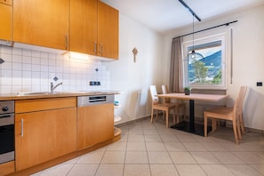 A modern kitchen with wooden cabinets, a built-in dishwasher, and a window with a view of a landscape.