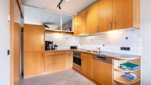 Una cocina moderna con armarios de madera, lavavajillas, horno y fregadero.