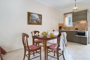A dining area with a table, chairs, and a painting on the wall.