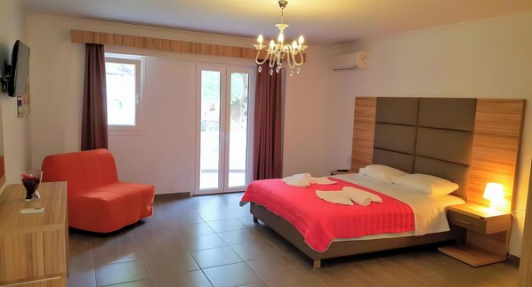 Un dormitorio con cama, mesita de noche, silla, escritorio y televisor.