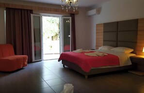Una habitación de hotel con cama, una silla roja, una puerta corrediza de vidrio y un candelabro.
