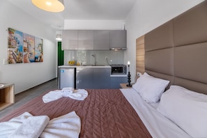 Una habitación de hotel con cama, una kitchenette pequeña y un cuadro en la pared.