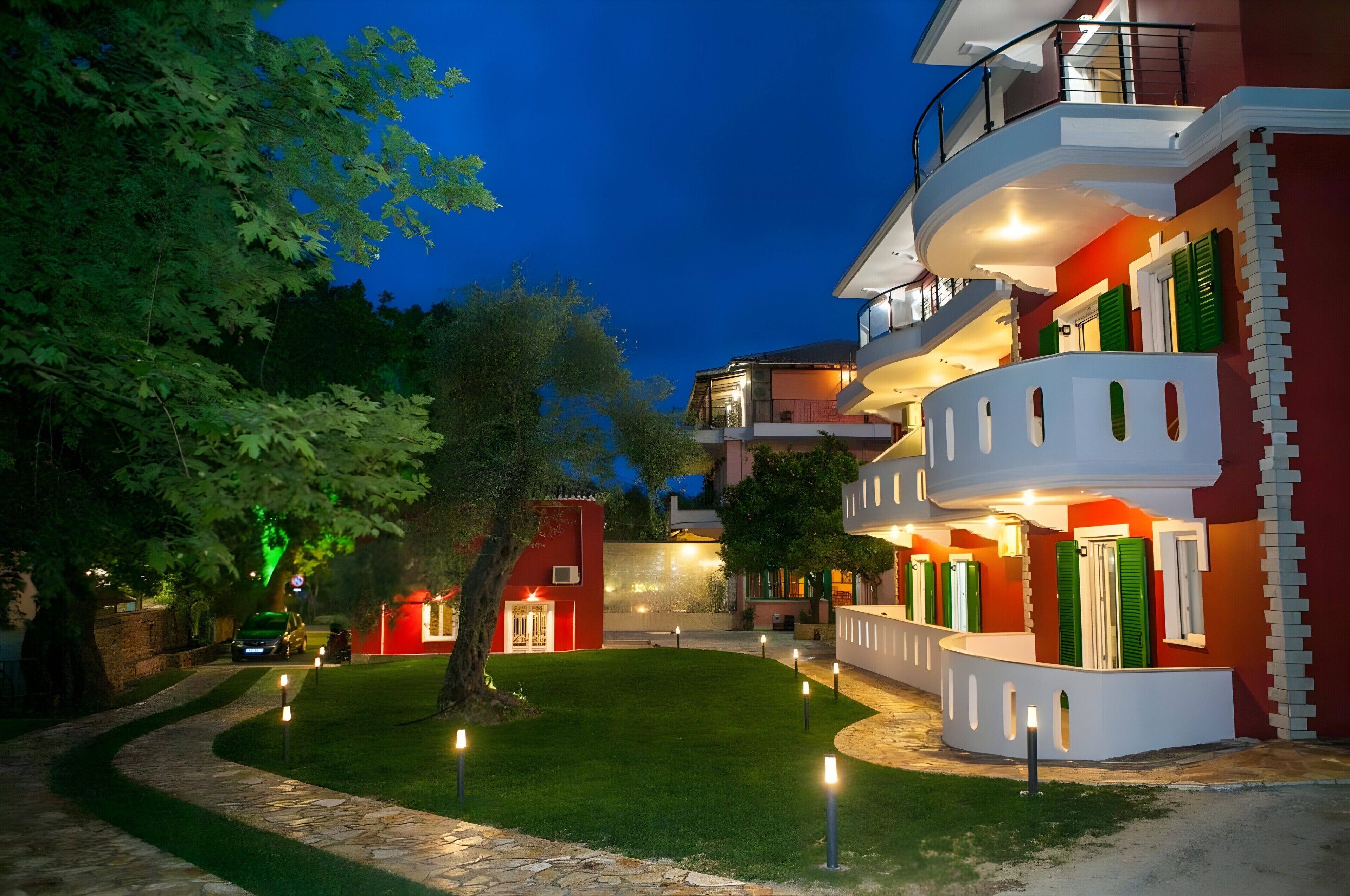A multi-story building with balconies, a well-maintained lawn, and a pathway.