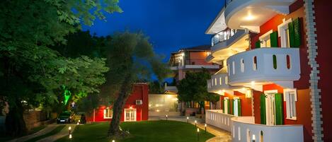 A multi-story building with balconies, a well-maintained lawn, and a pathway.