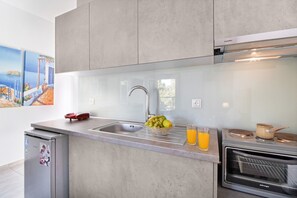 Une cuisine moderne équipée d’un évier encastré, d’un petit réfrigérateur, d’un four à micro-ondes et d’un verre de jus d’orange posé sur le plan de travail.