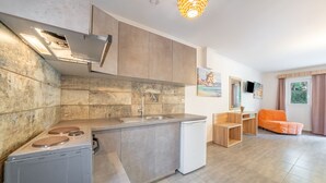 Eine moderne Küche mit Einbauherd, Spüle und einem kompakten Kühlschrank. Es gibt einen Essbereich aus Holz mit Tisch und Stühlen, sowie ein Fenster mit Vorhängen.