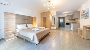 Ein modernes Hotelzimmer mit Bett, Nachttisch, eingebautem Kleiderschrank und einer Küchenzeile.