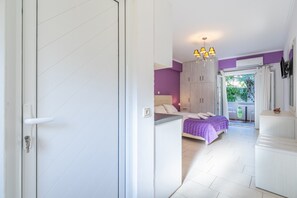Une chambre à coucher comprenant un lit, un bureau, une chaise, une armoire et un balcon avec vue.