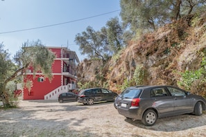 Um edifício com fachada vermelha, escadaria e carros estacionados.