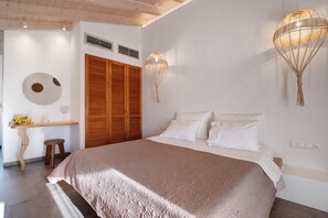A bedroom with a large bed, wooden wardrobe, and two wall-mounted lamps. - Room 'Deluxe Loft - B' with Shared Terrace, Wi-Fi and Air Conditioning (Parga)
