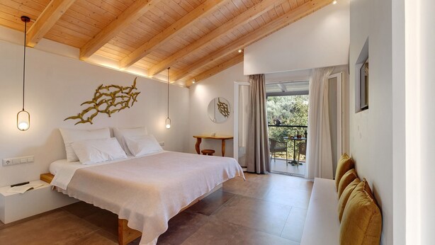 Quarto com cama, mesa de cabeceira, luminária e vista para o exterior.