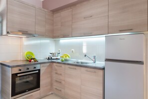 A modern kitchen with light wood cabinets, a stainless steel sink, and a built-in oven.