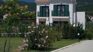 Un bâtiment à deux étages, doté d’un toit recouvert de tuiles, de volets verts et d’un balcon.