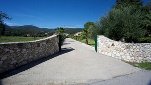 Un portail en pierre menant à une propriété offrant une vue sur les montagnes et la verdure.
