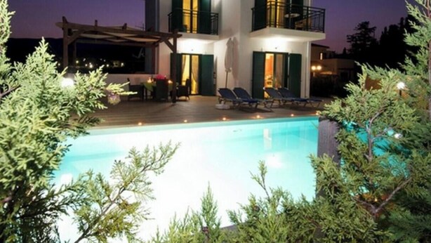Une maison à deux étages avec une piscine, un espace salon extérieur et un balcon.