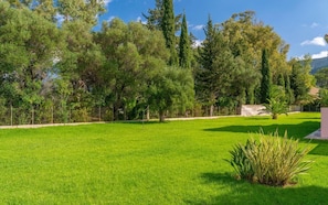 A well-maintained grassy area with a variety of trees and a stone structure.