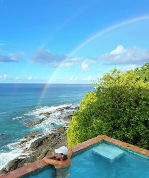 A person relaxing in a pool with a view of the ocean and a rainbow. - Enjoy amazing sea views, private pool & Caribbean breezes from this 2 bd villa! (La Vallee)