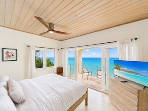 A bedroom with a bed, a ceiling fan, a TV, and a balcony with a view of the ocean. - Enjoy amazing sea views, private pool & Caribbean breezes from this 2 bd villa! (La Vallee)