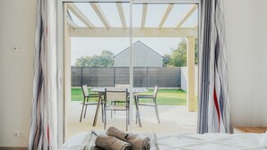 Un dormitorio con un ventanal grande, una cama y vistas a un patio exterior.