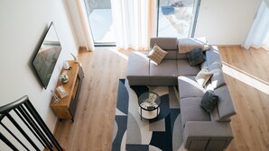 Una sala de estar moderna con un sofá modular, una mesa de centro y un televisor en la pared.