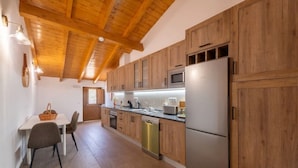 Une cuisine avec des meubles en bois, un réfrigérateur en acier inoxydable et un coin repas comprenant une table et des chaises.
