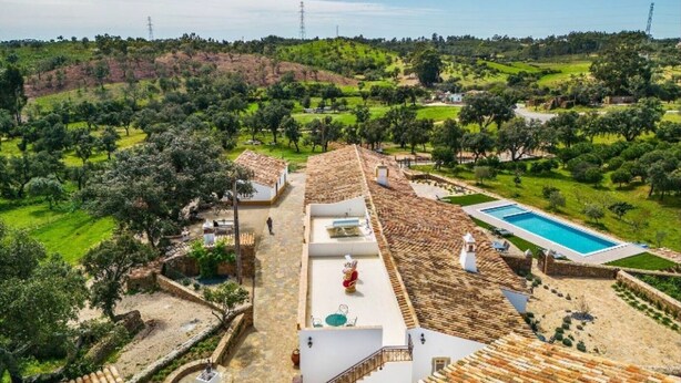 Une villa dotée d’une piscine, d’un toit recouvert de tuiles en terre cuite et offrant une vue sur la campagne environnante.