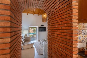 Une pièce avec un mur en briques, un plafond en bois, une télévision, un canapé et une vue sur une piscine.
