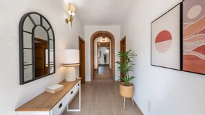 A hallway with a wooden console, a mirror, wall-mounted lamps, a potted plant, and framed artwork. - Holiday Home 'Casa Do Poço - Vale Luís Neto' with Mountain View, Wi-Fi and Air Conditioning (Loulé)