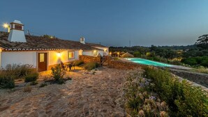 A stone house with a swimming pool, surrounded by greenery and a clear sky. - Holiday Home 'Casa Do Poço - Vale Luís Neto' with Mountain View, Wi-Fi and Air Conditioning (Loulé)