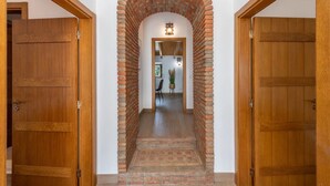 A hallway with a brick archway leading to a room with a wooden door. - Holiday Home 'Casa Do Poço - Vale Luís Neto' with Mountain View, Wi-Fi and Air Conditioning (Loulé)