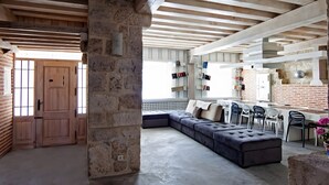 A spacious living area with a large sectional sofa, a dining table with chairs, and a kitchen area with built-in shelves. - Rural House 'La Casa Vieja De Vizmalo' with Hot Tub, Mountain Views & Garden in Burgos (Vizmalo)