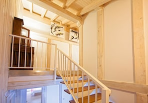 A wooden staircase with white railings leading to a room with a bed and a window.