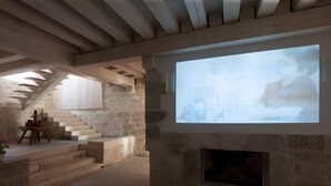 A room with a fireplace, stone walls, a staircase, and a large projection screen. - Rural House 'La Casa Vieja De Vizmalo' with Hot Tub, Mountain Views & Garden in Burgos (Vizmalo)