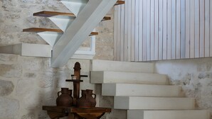 A staircase with white steps and a wooden handrail, leading to a room with a stone wall and a wooden table with pottery. - Rural House 'La Casa Vieja De Vizmalo' with Hot Tub, Mountain Views & Garden in Burgos (Vizmalo)