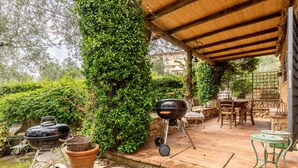 An outdoor patio with a wooden pergola, a barbecue grill, a table with chairs, and a stone wall. - Holiday Home 'Greg's House' with Private Pool, Garden and Wi-Fi (Santa Lucia)