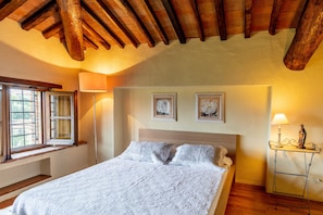 Une chambre à coucher avec un lit, une table de chevet, une lampe et deux tableaux encadrés accrochés au mur.