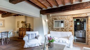 A living room with a stone wall, white furniture, and a candelabra. - Holiday Home 'Greg's House' with Private Pool, Garden and Wi-Fi (Santa Lucia)