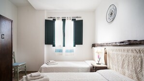 A bedroom with two beds, a wooden wardrobe, a chair, a bedside table with a lamp, and a decorative plate on the wall. - Villa 'Sa Curcurica' with Sea View, Private Terrace and Wi-Fi (Orosei)