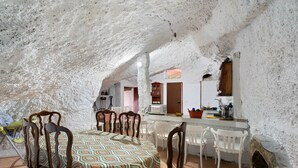 Ein Essbereich mit gemustertem Tischlein, Holzsesseln, einem gefliesten Boden in Weiß und einem Kamin aus Stein.