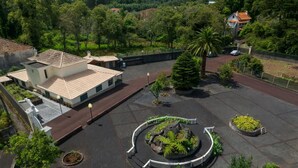 A courtyard with a central circular garden, surrounded by buildings with tiled roofs and a paved walkway. - Quinta dos Abutitos in Santo Ant nio da Serra (Santa Cruz)