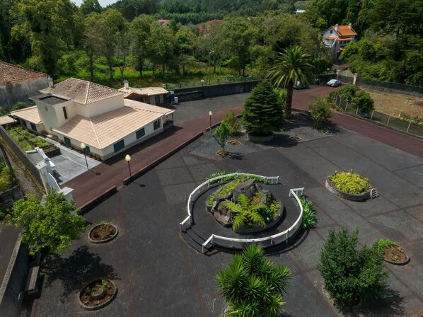 A courtyard with a central circular garden, surrounded by buildings with tiled roofs and a paved walkway. - Quinta dos Abutitos in Santo Ant nio da Serra (Santa Cruz)
