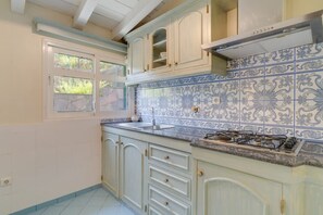 A kitchen with white cabinets, a gas stove, and blue patterned tiles.