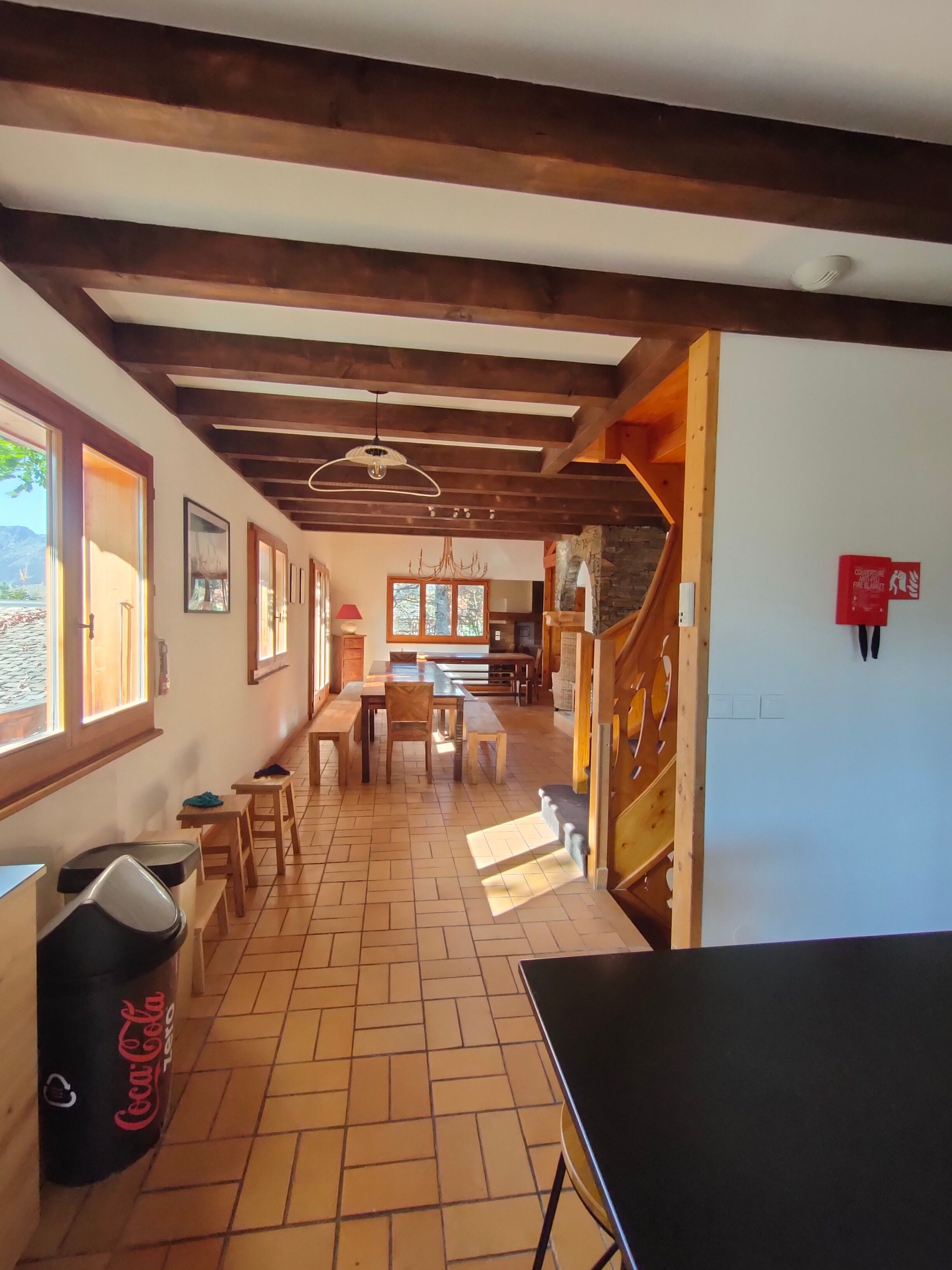 Un couloir avec des poutres en bois, un sol carrelé et un escalier menant à l’étage supérieur.
